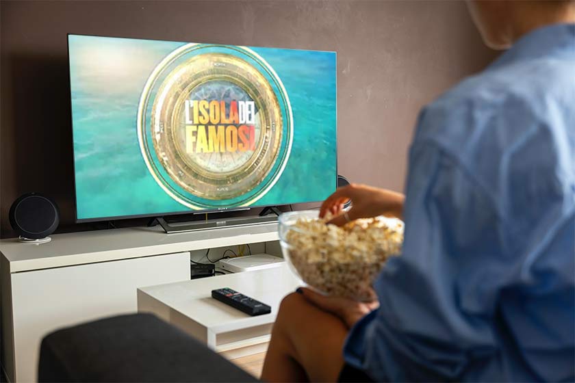 Spettatore guardando isola dei famosi streaming dal divano e con dei pop corn